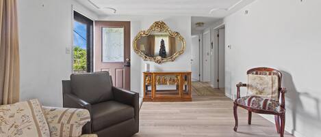 A spacious living area with a leather sofa, a patterned armchair, and a wooden side table with decorative items.