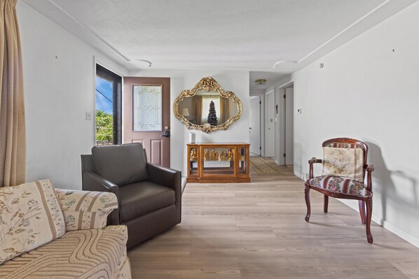 A spacious living area with a leather sofa, a patterned armchair, and a wooden side table with decorative items.
