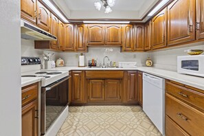 A kitchen with wooden cabinets, a stove, a microwave, and a dishwasher.