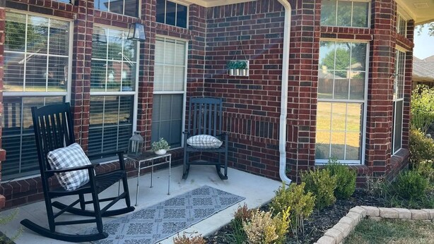 A corner house with a brick exterior, large windows, a porch with two rocking chairs, and a small table with a plant. - Relaxing Retreat Near Lake Lavon (Wylie)