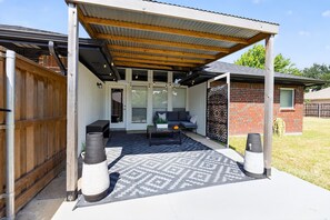 A covered outdoor seating area with a patio table and chairs, a decorative wall, and a wooden fence. - Relaxing Retreat Near Lake Lavon (Wylie)