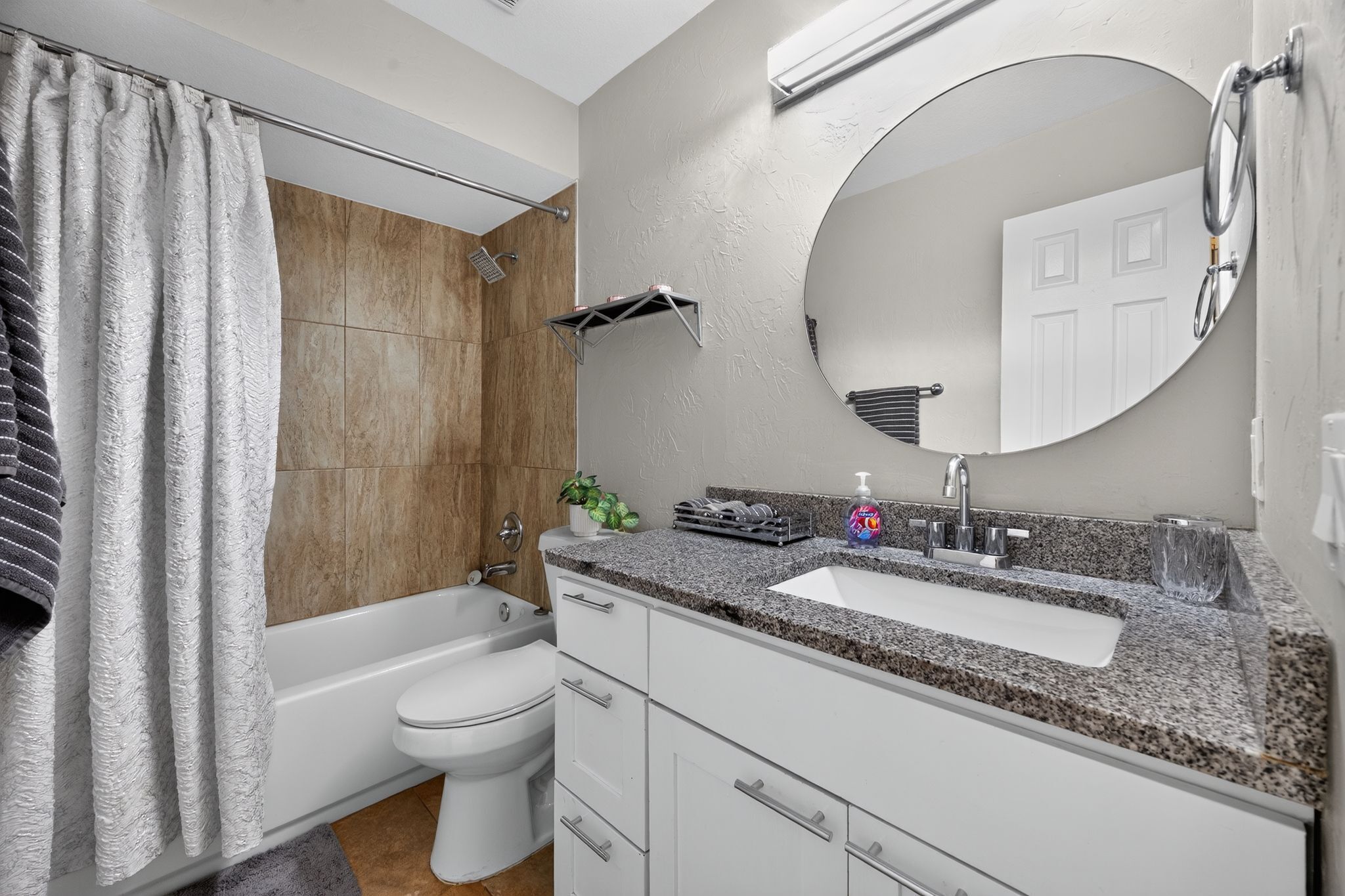 A modern bathroom with a bathtub, toilet, sink, and a large mirror.