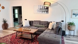 A modern living room with a sectional sofa, a coffee table, and a patterned rug. - 3-bedroom house in peaceful Foley perfect for relaxing getaways (Foley)
