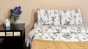 A bedroom with a bed, a nightstand, a painting, and a vase with flowers. - 3-bedroom house in peaceful Foley perfect for relaxing getaways (Foley)