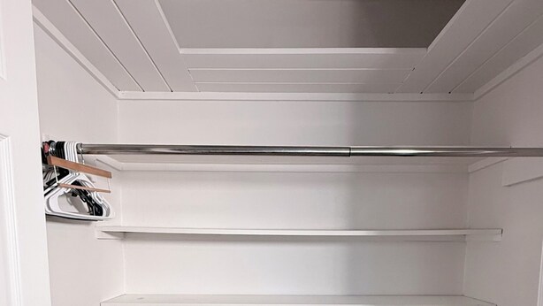 A walk-in closet with white shelving, a bench, and a trash bin. - 3-bedroom house in peaceful Foley perfect for relaxing getaways (Foley)
