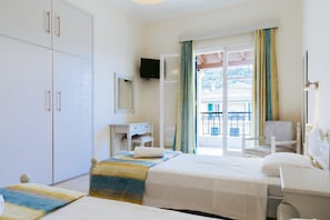 A hotel room with a bed, a desk, a chair, a wardrobe, and a balcony with a view. - Nikos Cassiopeia (Corfu)