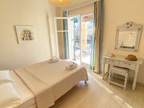 Ein Hotelzimmer mit Bett, Schreibtisch, Stuhl, Spiegel und einem fensterbepflanzten Fenster.