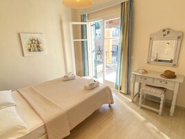 Habitación de hotel con cama, escritorio, silla, espejo y ventana con cortinas.