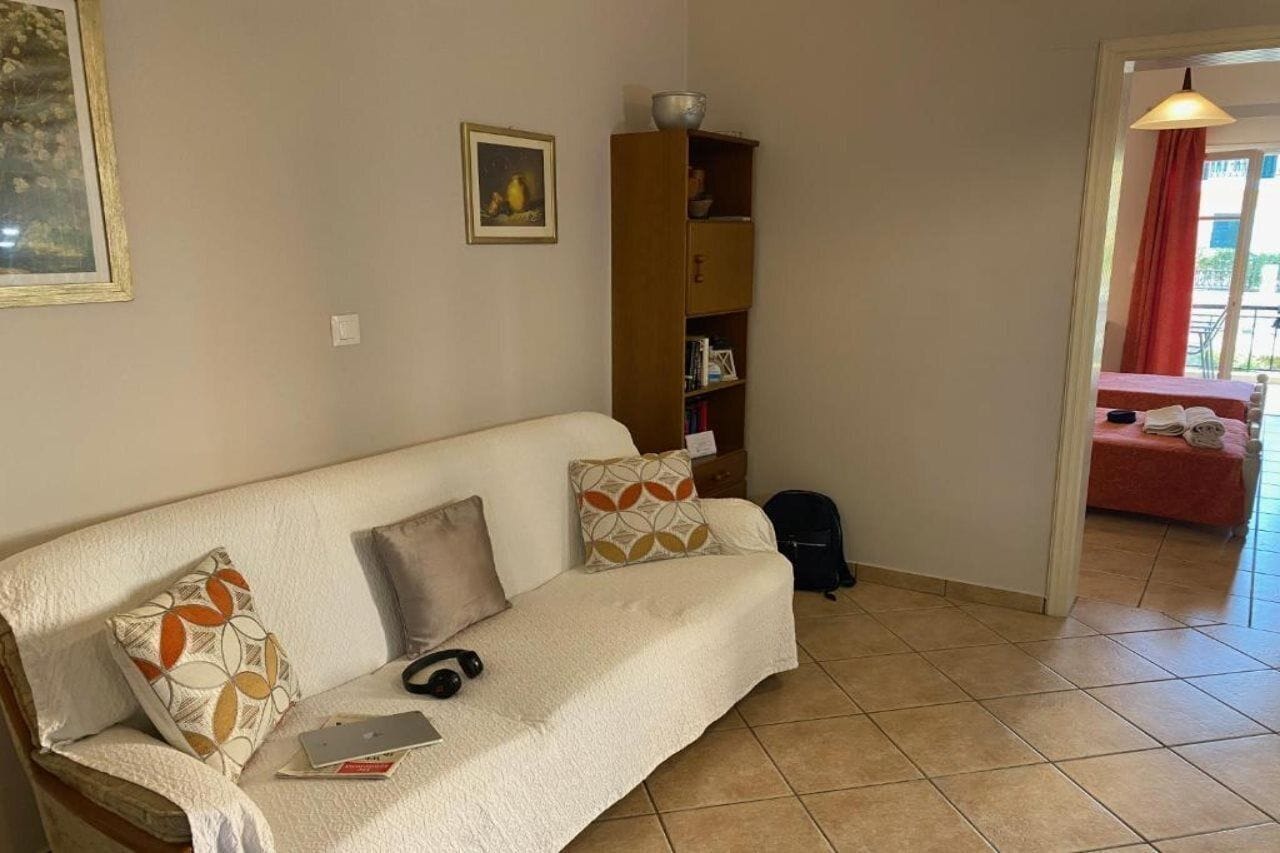 A living room with a sofa, pillows, a laptop, and a bookshelf.