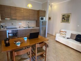 Una cocina compacta con armarios de madera, microondas, refrigerador y un comedor con mesa y sillas.