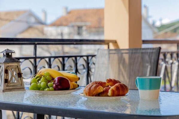 A table with a plate of food, a cup, and a lantern on a balcony. - Nikos Cassiopeia (Corfu)