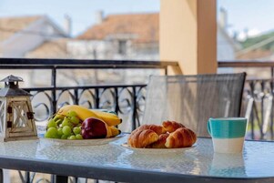 Una mesa con un plato de comida, una taza y un farol en un balcón.