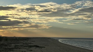 Une plage dotée d’un large rivage sablonneux et d’un ciel dégagé parsemé de quelques nuages.