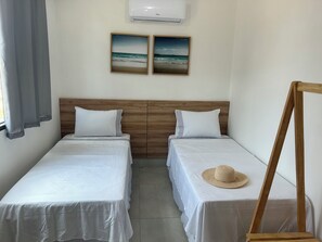 Ein Zimmer mit zwei Einzelbetten, einem Holzkopfteil, einem stehenden Spiegel und zwei gerahmten Bildern an der Wand.