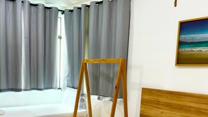 Une chambre d’hôtel avec deux lits, une tête de lit en bois, un tableau encadré au mur et une fenêtre avec des rideaux.