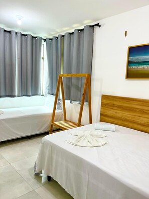 A hotel room with two beds, a wooden headboard, a framed picture on the wall, and a window with curtains. - Chaleville Barrinha (Cajueiro da Praia)