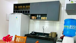 Une cuisine compacte équipée d’un réfrigérateur, d’une cuisinière et d’un distributeur d’eau.