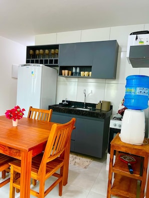 A compact kitchen with a refrigerator, stove, and a water dispenser. - Chaleville Barrinha (Cajueiro da Praia)