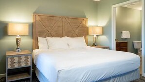 A hotel room with a large bed, two bedside tables with lamps, a wooden headboard, and a bathroom visible through an open door. - Escape to Massanutten: Your Ultimate July 4th Getaway! #1 (Massanutten)