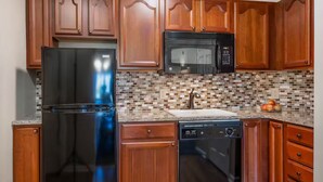 A kitchen with wooden cabinets, a stainless steel refrigerator, a microwave, a dishwasher, and a tiled backsplash. - Escape to Massanutten: Your Ultimate July 4th Getaway! #1 (Massanutten)