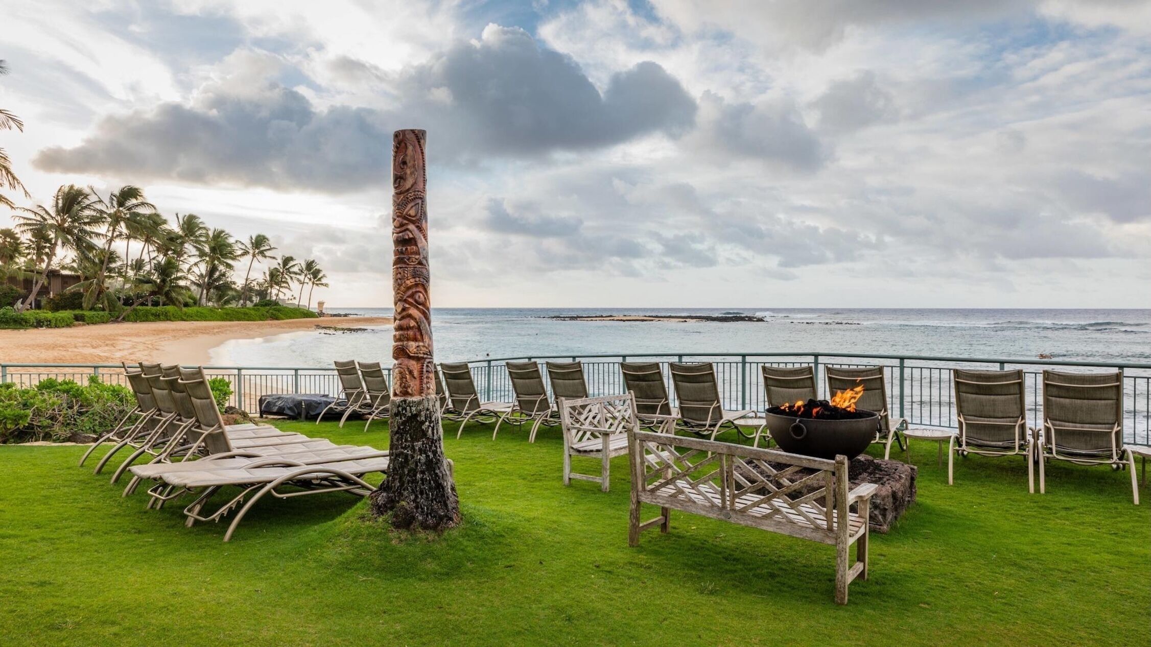 Un salón junto a la playa con sillones y una chimenea, con vista al océano.