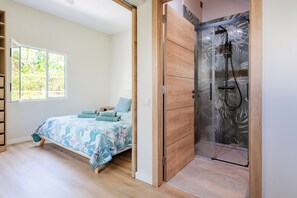 Ein Schlafzimmer mit Bett, Fenster, Dusche und einem Holzschrank.