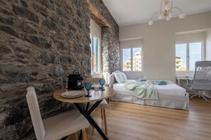 Ein Zimmer mit Steinsandsteinwand, einem Bett, einem Schreibtisch und einem Stuhl.