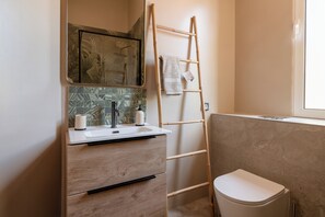 Ein Badezimmer mit einem Holzbidet, einem Spiegel, einem Waschbecken und einer Toilette.