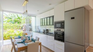 A modern kitchen with a large refrigerator, built-in oven, and microwave. - Dreamscape Levada (Funchal)