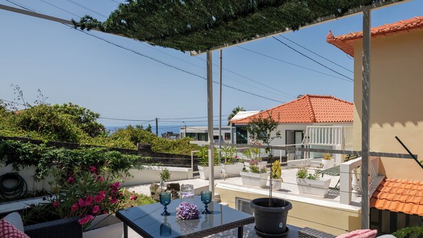 A rooftop terrace with a glass table, potted plants, and a view of the sea. - Dreamscape Levada (Funchal)