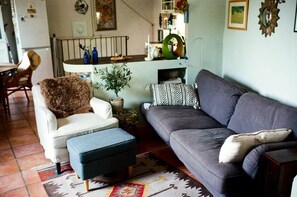 Een woonkamer met een bank, fauteuil, voetenbankje en een kamerbreed tapijt met een patroon.