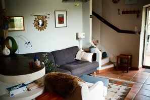 A living room with a grey sofa, a small table with a bottle, a potted plant, and a staircase leading to another level. - Provence Amour -Tranquil House w patio & parking (Cotignac)