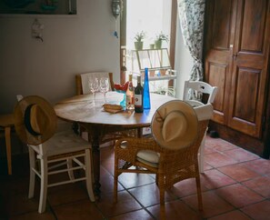 Een eettafel met stoelen, twee wijnglazen, een fles en een decoratief object.