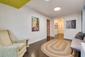 Een woonkamer met een bank, een stoel, een vloerkleed en kunstwerken aan de wanden.