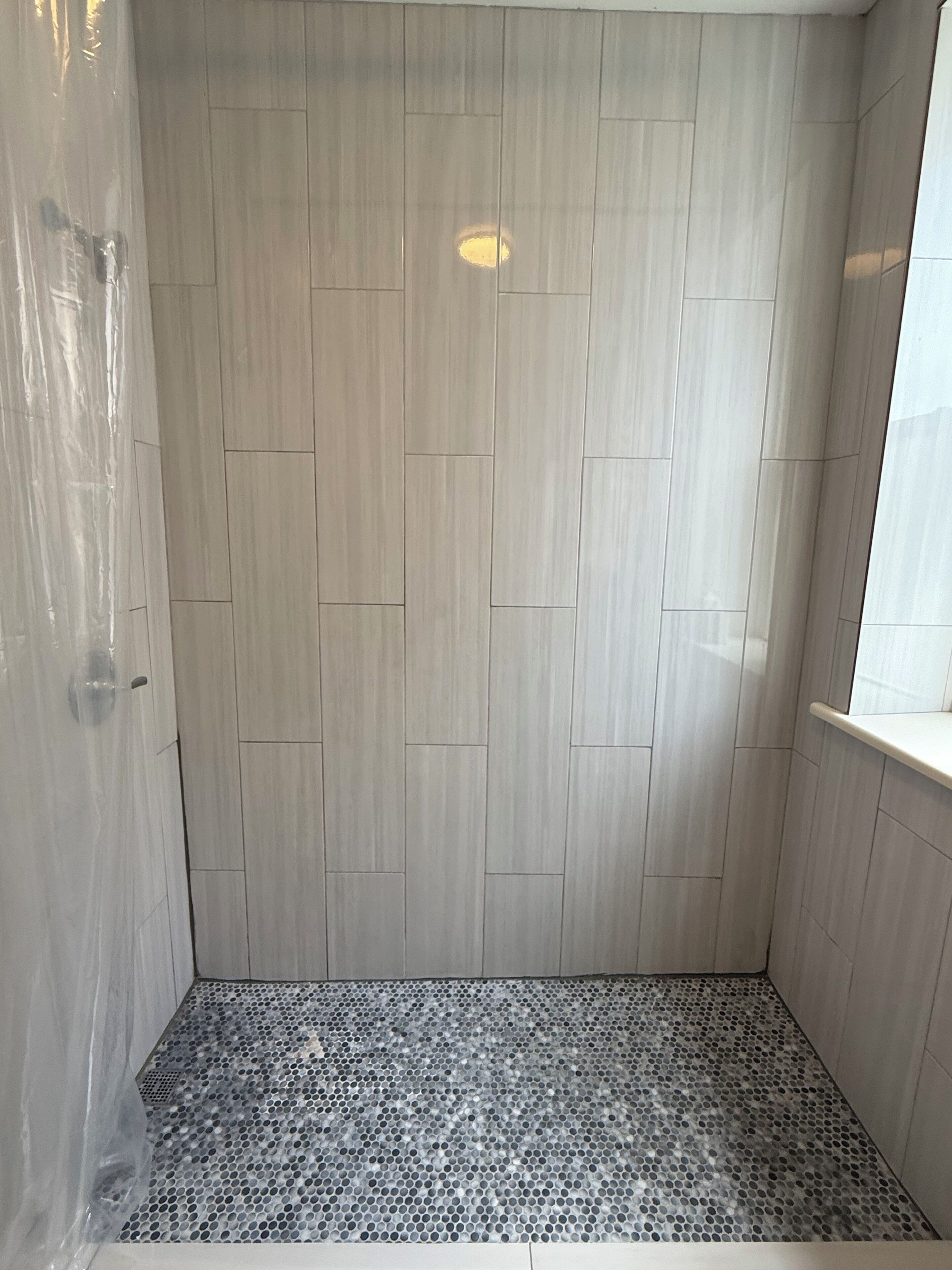 Une douche avec un sol carrelé et des murs en bois.
