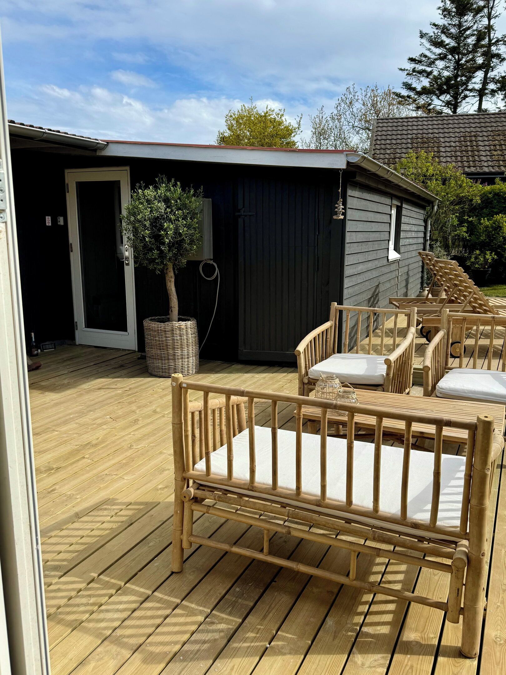 A wooden deck with outdoor furniture, a dark building in the background, and a clear sky.