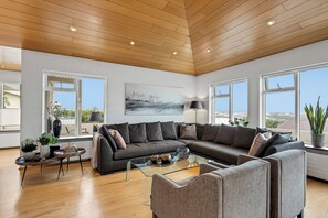 Ein modernes Wohnzimmer mit einem Ecksofa, einem Glastisch und einem Gemälde an der Wand.