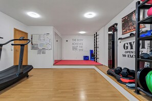 Een fitnessruimte met trainingsapparatuur, een rode mat en motiverende muurkunst.