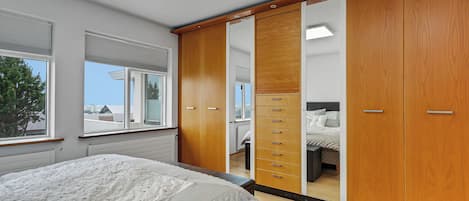 A bedroom with a bed, a wardrobe, and a window.