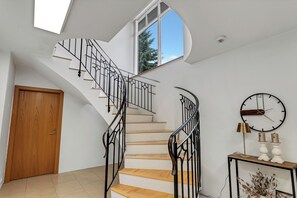 A modern staircase with black railings and wooden steps, leading to a second floor with a skylight. - Spacious 340 m² Home with Stunning City & Mountain Views, Gym and Garden (Reykjavík)