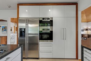 Eine moderne Küche mit einem Edelstahl-Kühlschrank, einem eingebauten Backofen und einem Wasserspender.