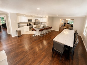 A spacious kitchen with a central island, bar stools, and a dining table with chairs.