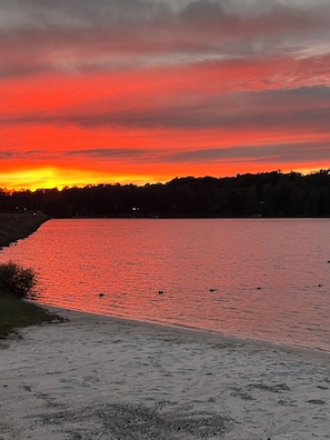 A sunset over a calm lake with a shoreline.