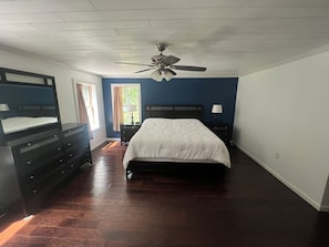 A bedroom with a bed, dresser, nightstand, and ceiling fan.