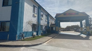 Un edificio con fachada azul y blanca, una entrada cubierta y un letrero digital que muestra 'WELCOME!'. 
