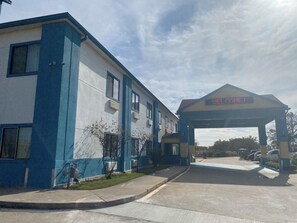 Un edificio con fachada azul y blanca, una entrada cubierta y un letrero digital que muestra 'WELCOME!'. 