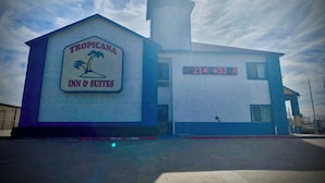 Edificio del Tropicana Inn & Suites con un letrero llamativo y una pantalla digital que muestra el número 214 453 8.
