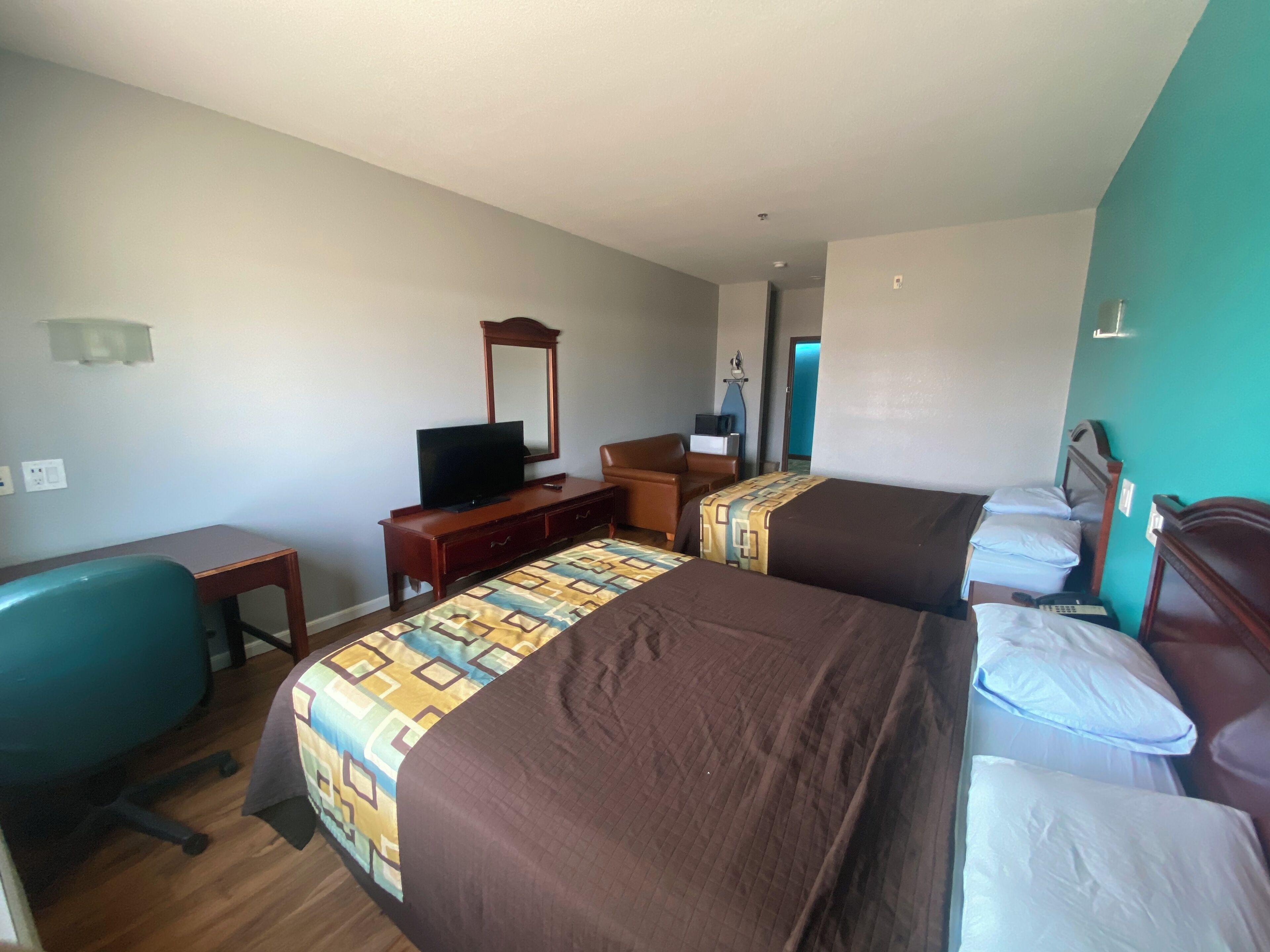A hotel room with two beds, a desk with a television, a chair, and a dresser.
