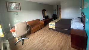 Una habitación de hotel con cama, sofá, escritorio y ordenador, además de una silla.