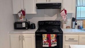 A kitchen with white cabinets, a black stove, and a microwave.